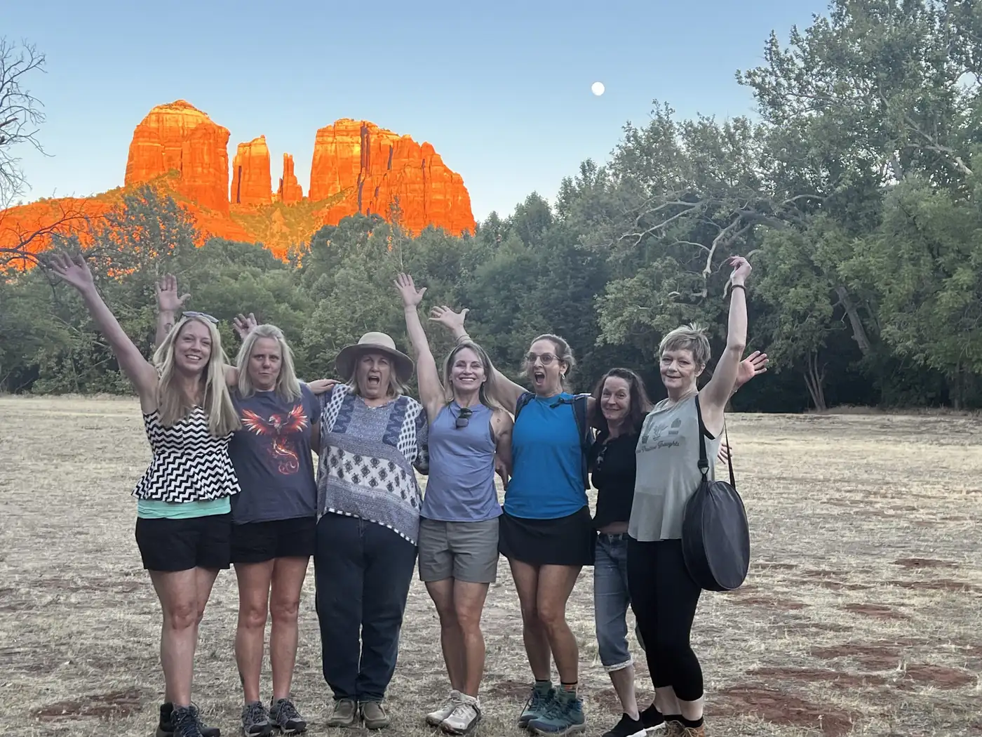 A group of women standing together outdoors with their arms raised
