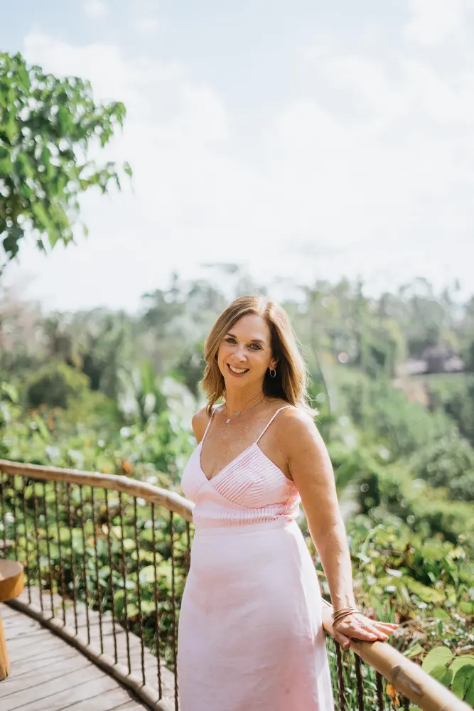 Julie Wright Halbert smiling at a rail above a green valley in Bali